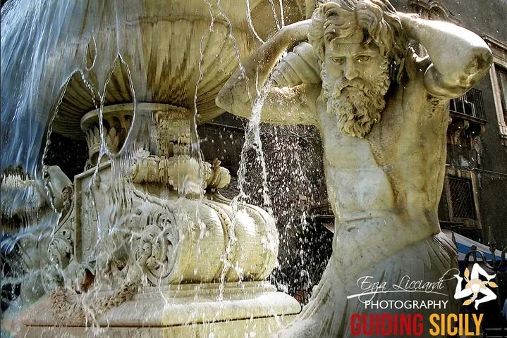 Wasser stürzt über eine Marmorbrunnenstatue eines bärtigen Mannes mit einer Muschel.